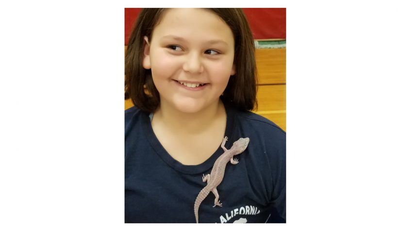 Girl with lizard crawling on her shirt.